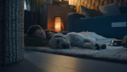 Girl lying on mild carpet with dog, sleeping together, feeling relaxed after saturated day, spending leisure time at home. Golden retriever.