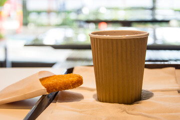 hot coffee in brown paper cup, coffee in white desk, Takeaway coffee in cafe shop, on blur background