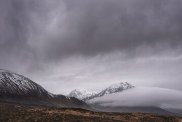 Beautiful Winter landscape of Buachaille Etive Mor Stob Dearg in Scottish Highlands engulfed in low cloud with snowcapped peaks