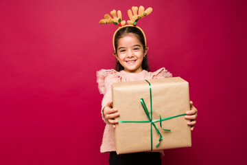 Happy little girl smiling giving a christmas present