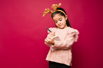 Adorable young kid writing her christmas wishes to santa