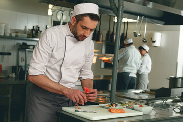 Professional Male Chef in uniforms preparing sushi in a kitchen of asian restaurant