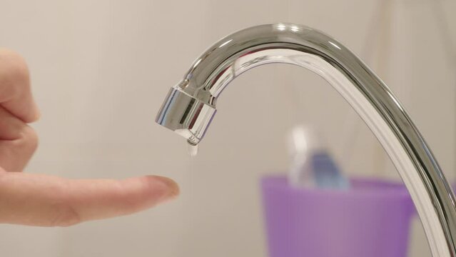 Doigt qui avance pour v&eacute;rifier la fuite d'un robinet de salle de bain