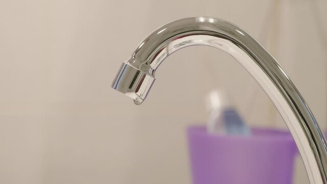 Main qui avance pour v&eacute;rifier la fuite d'un robinet de salle de bain