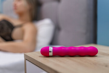 Young woman holding sex toy dildo vibrator in bed - obrazy, fototapety, plakaty