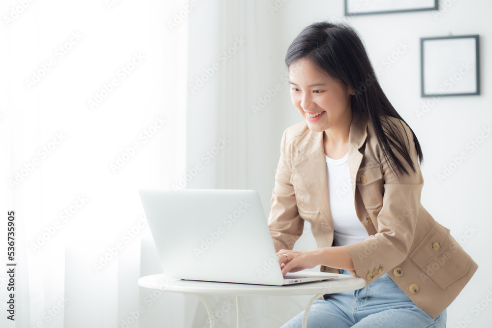 Wall mural young asian businesswoman working on laptop computer on desk at home office, freelance looking and t