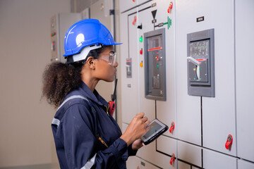 Electrical young asian woman engineer examining maintenance cabinet system electric and using...