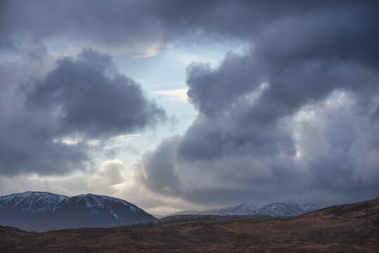 Winter dramatic stormy skies landscape image over snowcapped mountains in Scottish Highlands