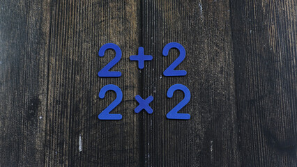 Task in mathematics. Mathematics problem for children. Simple algebra examples using numbers and signs from plastic numbers on a wooden background.