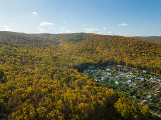 The concept of an ecological village. A combination of nature and ecology. The village between the mountains, the view from the drone. Aerial photography of autumn. Golden Autumn