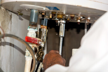 A technician repairs a leaking boiler using pliers