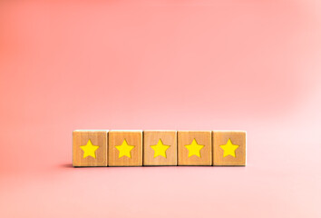 Client feedback survey with yellow star on five wooden cube blocks on pastel pink background with...