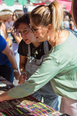 Two women shopping in an Arab market. Tourists choosing gifts to buy in a city market. Concept of street shopping. Vertical image