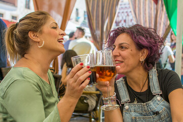 Cheerful Mature Friends In Casual Clothes Sitting At A Table With A Glass  Toasting And Laughing On A Restaurant Terrace. Lifestyle