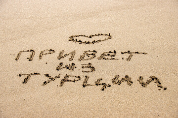Inscription on wet sand Hello from Turkey. Russian language. Concept photo of summer vacation