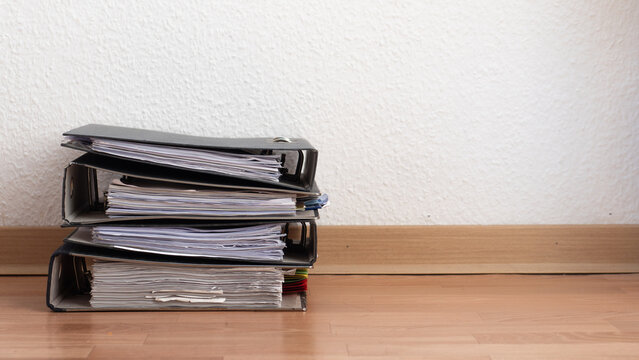 Buchhaltung und Papierkram: Stapel von Ordnern mit Unterlagen vor wei&szlig;er Wand mit Platz f&uuml;r Text