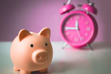 Pink alarm clock with pink piggy bank. Saving money for future plan and retirement fund concept.