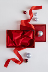 Christmas scene with a red gift box and red Christmas baubles on white background. Christmas promo.