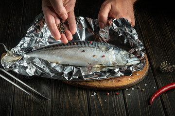 Close-up of chef hands while preparing delicious scomber or mackerel. Delicious recipe for baking fish in foil