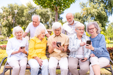 Group of seniors people bonding at the park - Elderly old people using smartphones to shop online and visit social media app