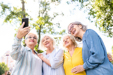 Group of seniors people bonding at the park - Beautiful old female friends using modern smartphone technology and social media app