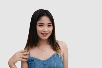 A smiling young woman wearing a denim top poses for the camera for a studio shot isolated on a white background.