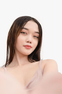 A smiling young woman taking a selfie using the front camera. Studio shot isolated on white background.