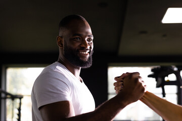 Handshake of sporty african man with woman greeting partner exercise workout at fitness gym.