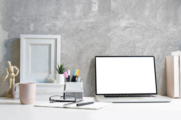 Stylish workplace with laptop computer, coffee cup, stationery and picture frame.