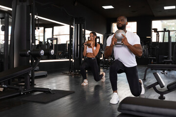 Fototapeta na wymiar Fitness couple in sportswear doing squat exercises at gym.