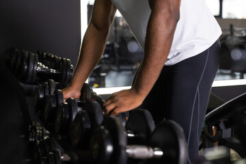Plakat Fitness african man in training showing exercises with dumbbells in gym.