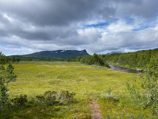 Fototapeta na wymiar Lanschaft am Klimpfjäll nahe der 7 forsar mit Blick auf Berg und Fluss am Vildmarksvägen, Lappland, Västerbotten, Schweden