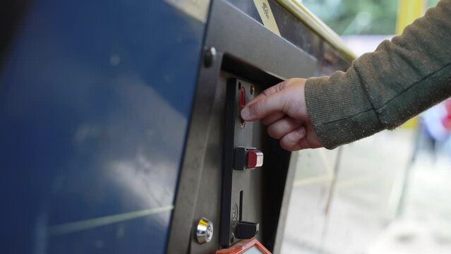Hand of boy is trying to throw coin into slot machine, close-up.