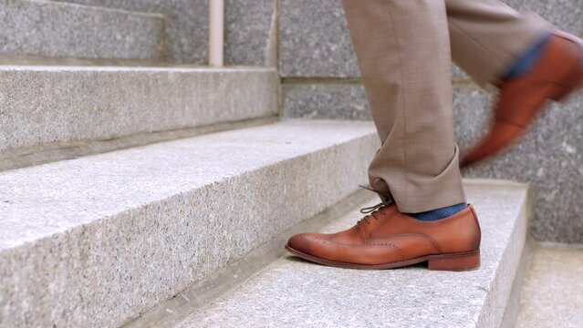 Closeup of the shoes of a lawyer or businessman wearing a suit walking up the granite steps of a town hall or courthouse city building.