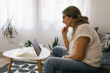 Adult woman having video call at home using tablet