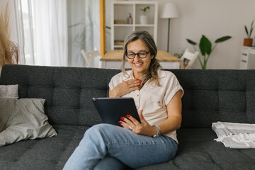 Adult woman having video call at home using tablet