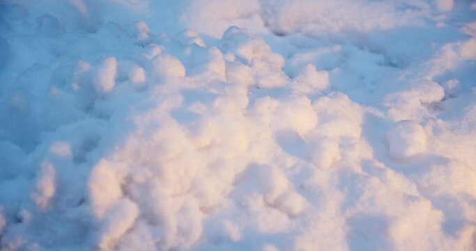 close-up flying over a snow-covered ground. Natural winter background with snow drifts during dusk time. view of the white freshly fallen snow after a snow storm in the winter. 
