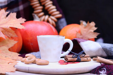 Cup with coffee or cocoa on the background of bright ripe pumpkins. Cozy warm still life. A composition of items that create an autumn mood and atmosphere