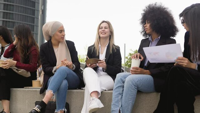Multiracial business women taking a break for eating a meal and talking outside the office