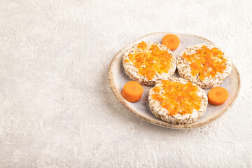 Carrot jam with puffed rice cakes on gray concrete. Side view, copy space.