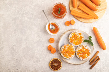 Carrot jam with puffed rice cakes on gray concrete. Top view, copy space.
