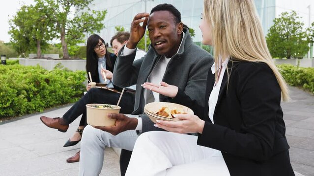 Happy multiracial business people having a lunch break outside office