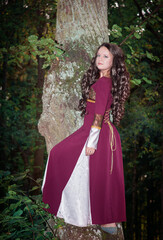 Obraz na płótnie Canvas Young beautiful woman wearing medieval style dress standing near tree outdoor