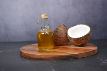 Obraz na płótnie Canvas slice of fresh coconut and bottle of oil on a black background 