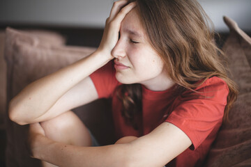 Sad thoughtful teen girl sits on couch