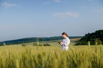Laboratory-technician using digital tablet computer in a cultivated wheat field, application of modern technologies in agricultural activity