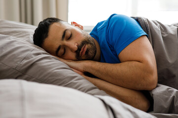 A young guy of oriental appearance sleeps at home in bed, sees good dreams, copy space