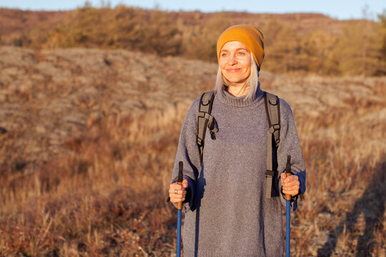 Attractive Short Haired Middle Aged Woman In Activewear Hiking In Forest Using Poles For Nordic Walking