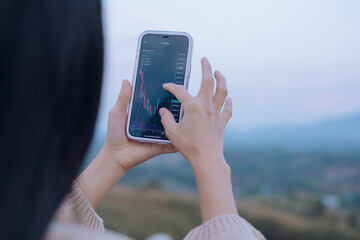 Woman is checking Bitcoin price chart on digital exchange on smartphone, cryptocurrency future price action prediction.