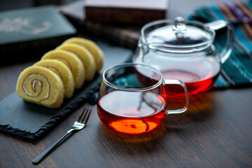 ガラス製のカップに入った紅茶とスレートプレートに乗ったロールケーキ
